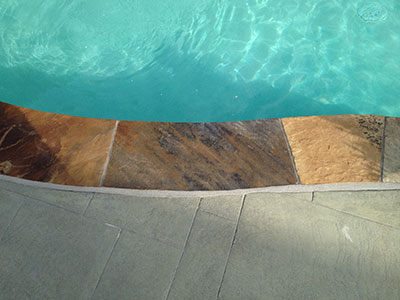AFTER Textured stone border around a clear, blue swimming pool.
